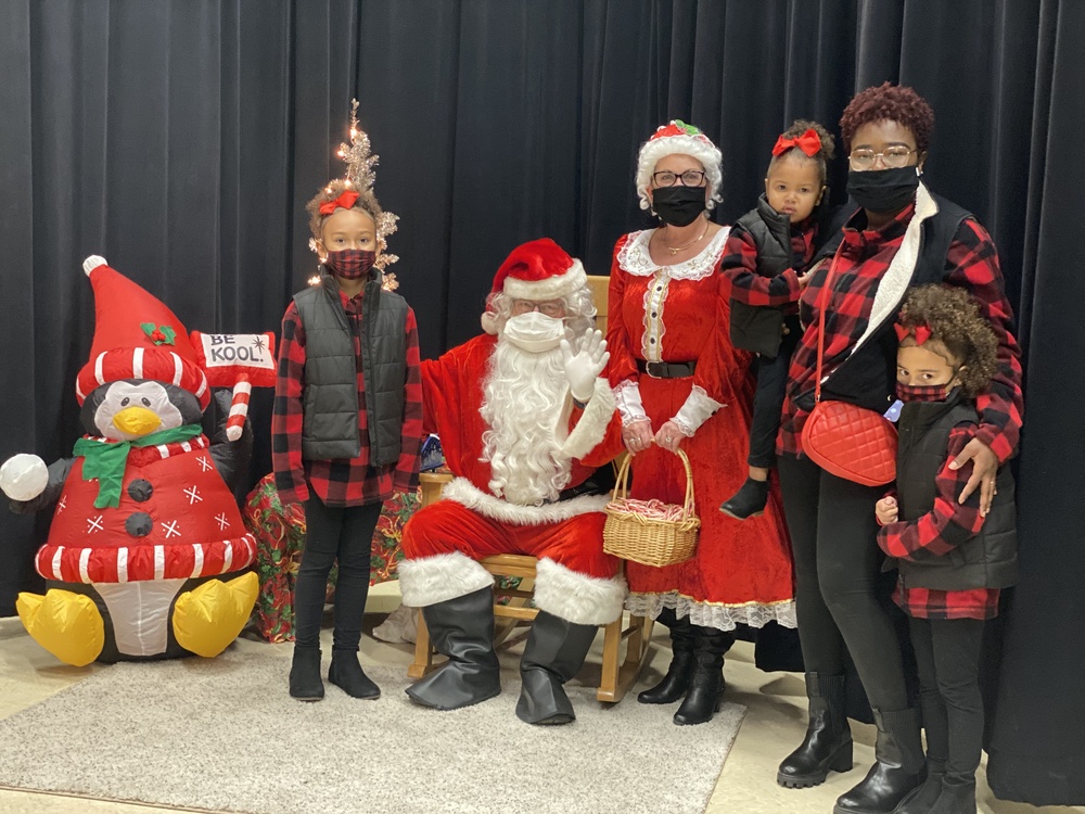family with matching outfits poses with Santa and Mrs. Claus for a picture